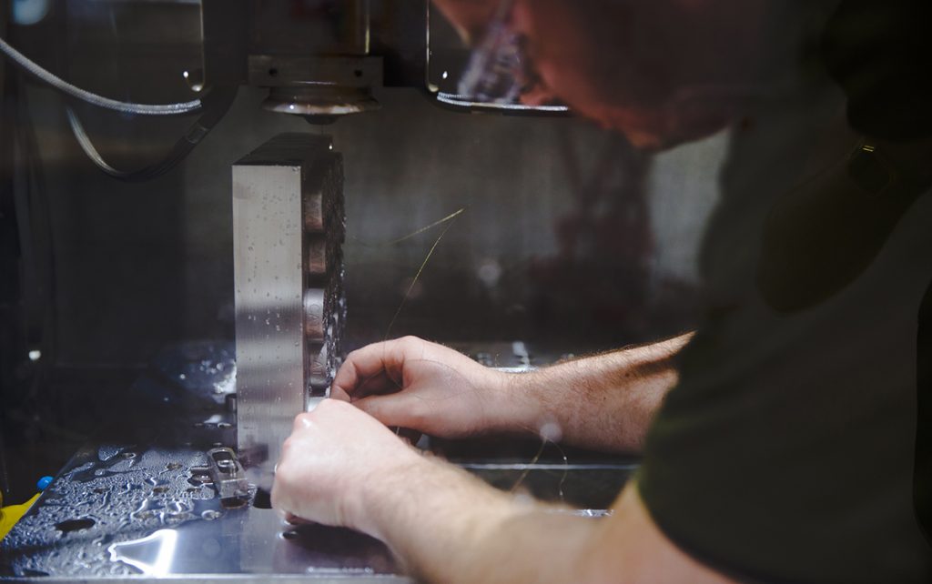 Fig. 9 A CATA worker using an electric discharge machine to separate AM parts from the support plate (Image: GE Reports/Chris New) [15]