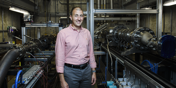 Associate Professor Carson Slabaugh with combustion test rigs at Purdue University’s Zucrow Labs (Courtesy Velo3D/Purdue University)