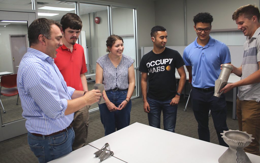 Fig. 4 Ohio State CDME staff and student researchers examining additively manufactured metal gas turbine components, including the SGT-700 
