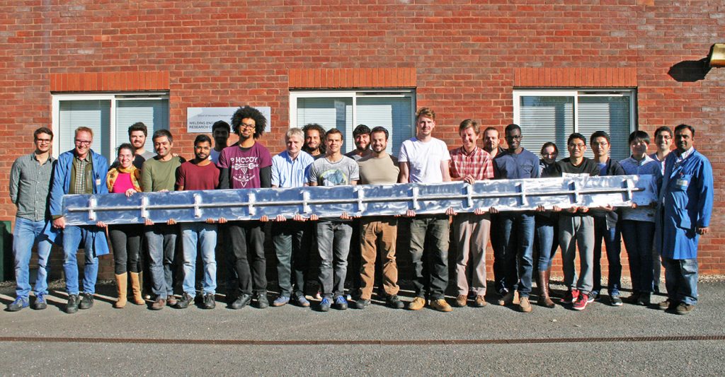 Fig. 8 A 6 m long aluminium spar demonstrator, built at Cranfield University in 2016 on a large prototype WAAM system featuring multiple robots and a 10 m long build envelope (still in use today), in the as-built condition. The part demonstrated distortion control over even larger scales than before, laying the foundations for subsequent multi-metre titanium parts. The picture was taken outside Cranfield University’s Welding and Additive Centre