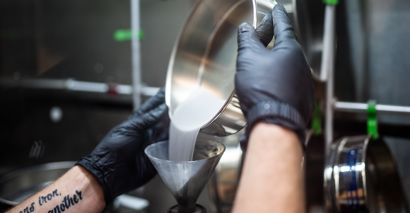 A hopper is filled with the raw materials to additively manufactured (Courtesy Craig Fritz/Sandia National Laboratories)