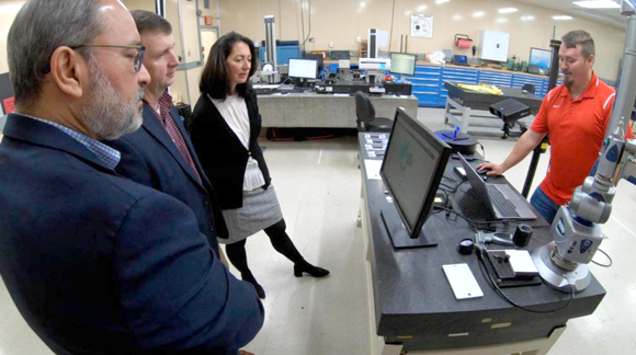 Cody Hagood (right) from the US Army Redstone Test Center, demonstrates how an additively manufactured fuel elbow for the UH-60 Black Hawk (Photo by Nutan Chada)