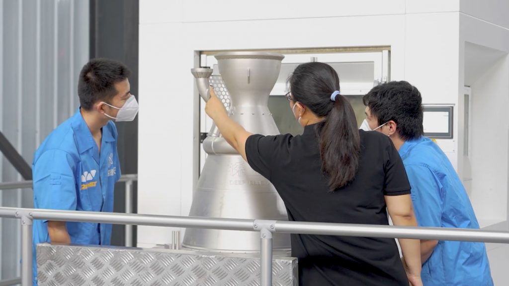 Fig. 2 Deep Blue Aerospace employees examine an as-built combustion chamber produced on Farsoon's FS621M PBF-LB machine (Courtesy Farsoon Technologies)