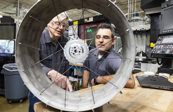 NASA mechanical design engineer Richard Hagen, left, and ORNL researcher Michael Borish inspect a lunar rover wheel prototype that was additively manufactured at the Manufacturing Demonstration Facility (Courtesy Carlos Jones/ORNL, U.S. Dept. of Energy)