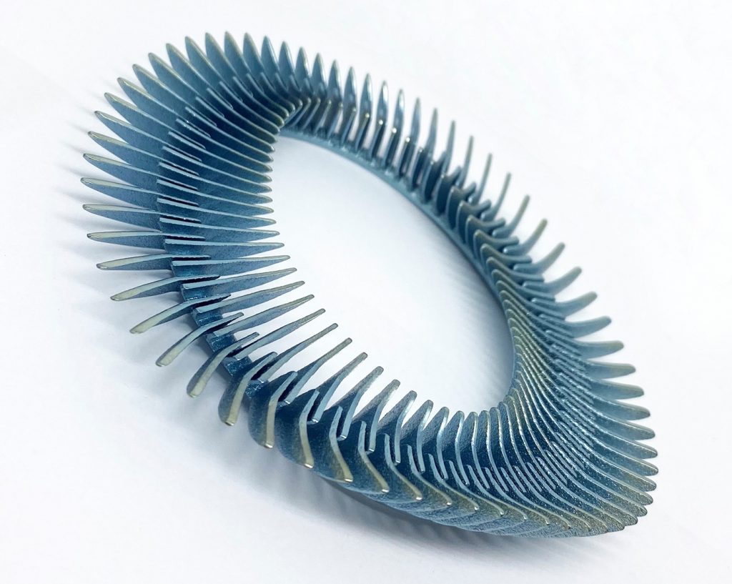Fig. 1 'Vertebrae 264' brooch (2020), designed by Stefania Lucchetta. Materials are anodised titanium and steel. Laser Beam Powder Bed Fusion (PBF-LB) was the primary technology used. The piece is hand finished using sandblasting and polishing (Courtesy Stefania Lucchetta)