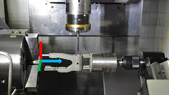 Photo shows a hitch-shaped machine part clamped in a large device. A probe that is tipped with a small red sphere sits just above the machine part (Courtesy North Carolina State University)