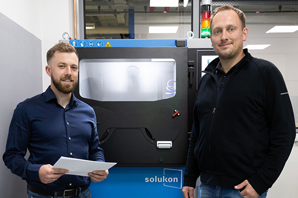 Peter Scherer, Head of Additive Manufacturing and Josef Weissthanner, Technologist & Specialist Additive Manufacturing at Rohde & Schwarz in front of the new Solukon depowdering system (Courtesy Rohde & Schwarz)