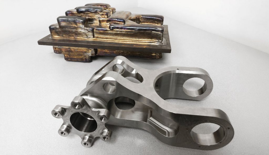 Fig. 15 DED Ti-6Al-4V landing gear structural component as an as-built preform and post-machined, delivering significant cost and lead-time savings compared to the legacy component. Note the double-sided use of the build plate for efficient fabrication (Courtesy General Atomics Aeronautical Systems Inc (GA-ASI))