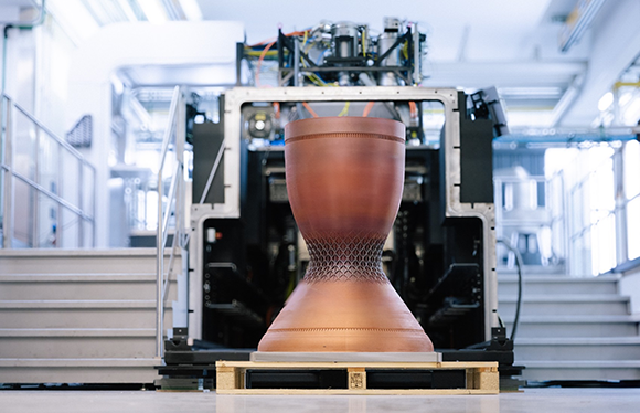 Copper additively manufactured demonstration combustion chamber (800 × 800 × 1200 mm), shown in front of the AMCM M 8K prototype machine (Courtesy AMCM)