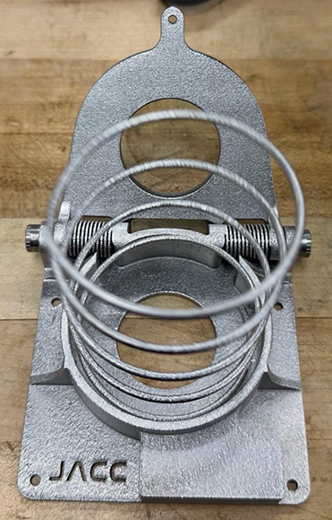 Close-up of the additively manufactured titanium deployment spring within the JPL Additive Compliant Canister (JACC), showcasing the embedded mechanism architecture enabled by Additive Manufacturing (Courtesy Douglas Hofmann / NASA JPL)