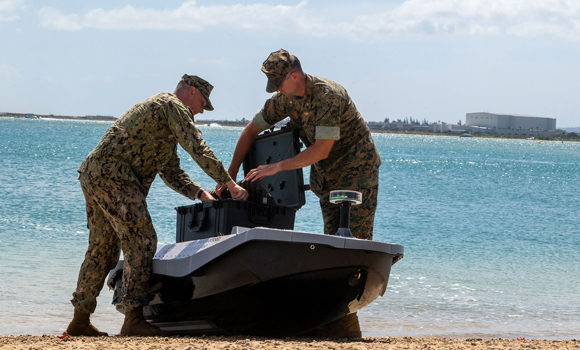 NPS student US Navy Lt Evan Humphreys and Marine Corps Lt Col Michael Radigan load cargo onto a digitally crewed surface vessel at the Honolulu Harbor Public Boat Ramp in Honolulu (Courtesy US Navy/Mass Communication Specialist Seaman Katherine Eldridge)
