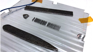 The SmartPlate pictured has optical strain gauges and thermal sensors built into the metal. The printed geometry on top was built using Powder Bed Fusion while simultaneously recording strain/time and temperature/time data (Courtesy Fabrisonic)