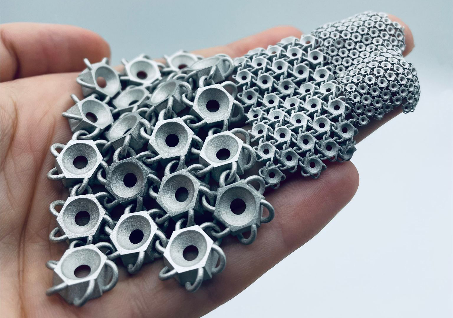 Fig. 1 Additively manufactured steel chain in three sizes, produced via LMM, in the as-sintered stated prior to surface polishing (Courtesy Incus)