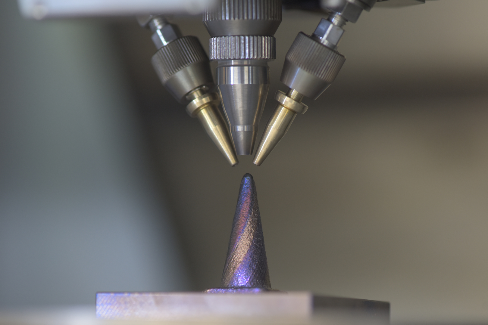 Fig. 10 Nikon Lasermeister DED head above a cone-shaped deposition sample used to demonstrate multi-material processing (Courtesy Nikon)
